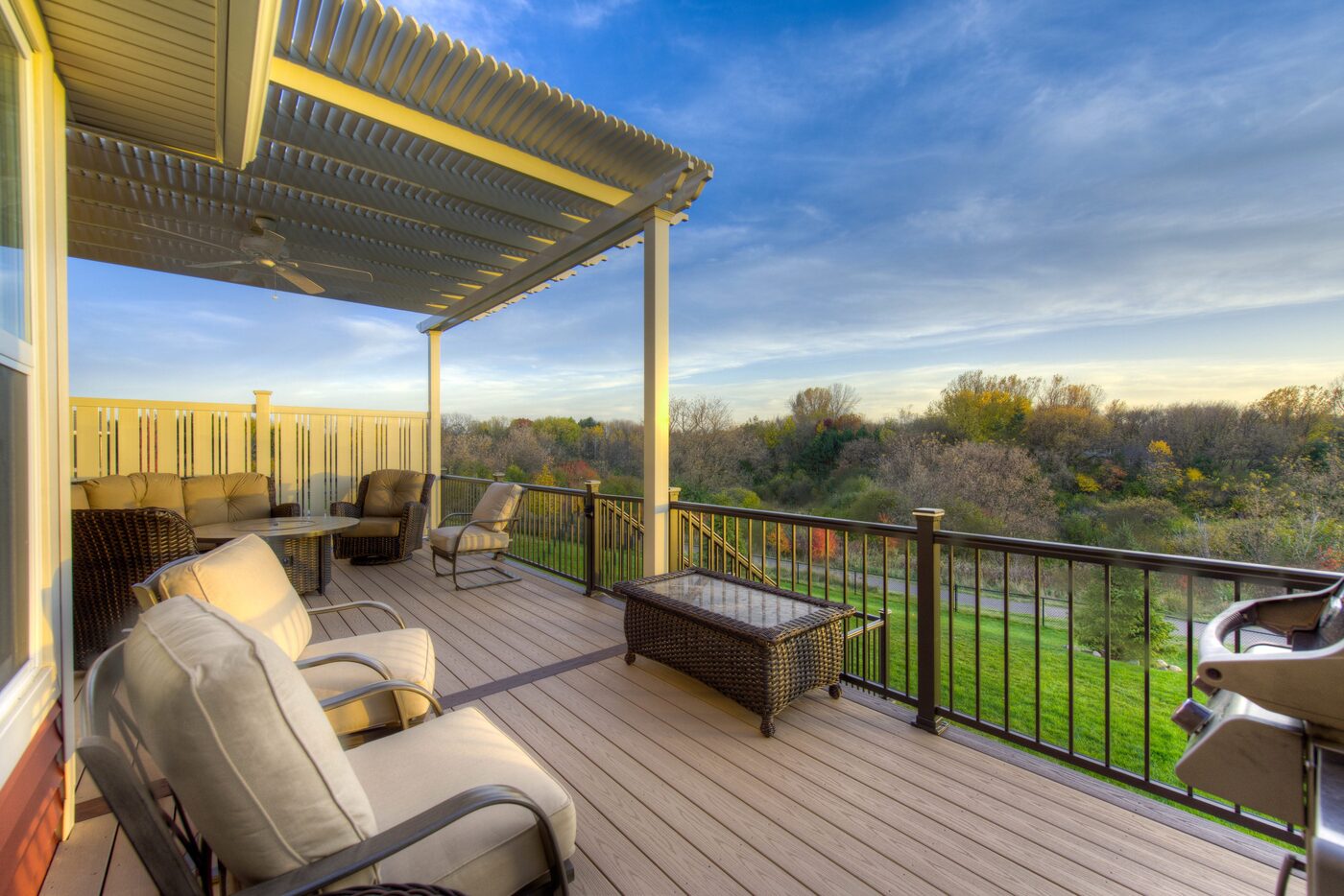 Covered composite deck with black railing and wooded view